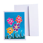 Load image into Gallery viewer, A hand painted pure silk original art card greeting card with a colorful floral design in front of a plain white envelope on a white background. The card features stylized flowers in pink, red, yellow, and purple on a bright blue background.
