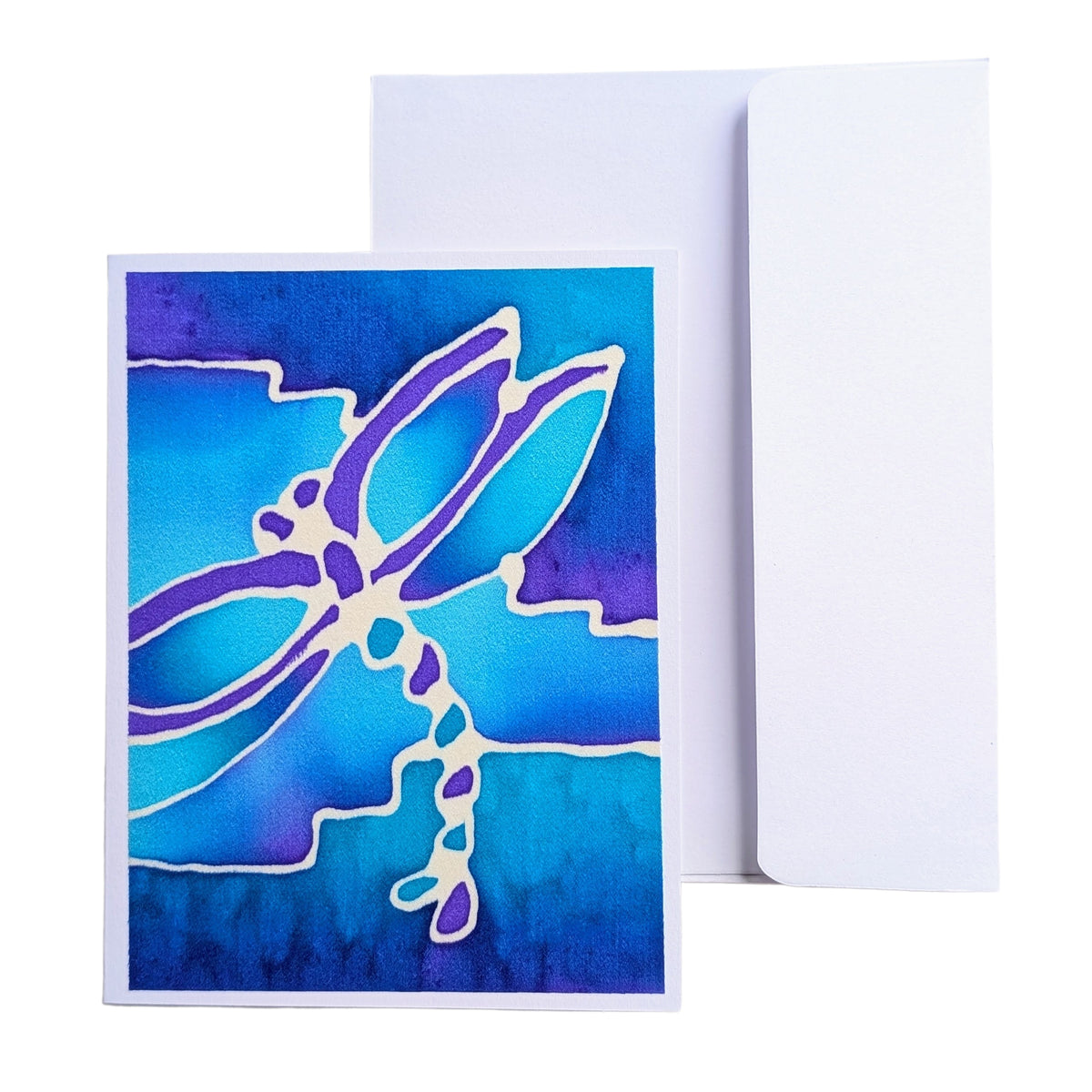 A hand painted pure silk art original  greeting card featuring a stylized dragonfly design in blue, purple, and white, shown with a plain white envelope behind it on a white background.