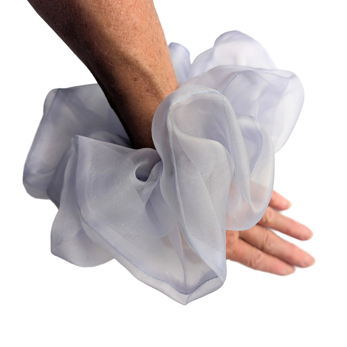 A sheer, ruffled wrist pure silk ORGANZA Oversized scrunchie cuff in a pale lavender-gray color, worn on a person's wrist with their hand resting 