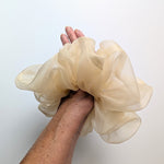 Load image into Gallery viewer, A large, voluminous sheer pure silk organza  hair scrunchie in a light champagne beige color, being worn on the wrist
