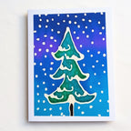 hand painted pure silk original art greeting card featuring a hand-painted green Christmas tree with white snow details against a blue and purple gradient background with white snow dots,