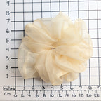 A cream-colored pure silk organza oversized jumbo hair scrunchie   displayed on a white grid ruler with inch and centimeter markings to show its size.
