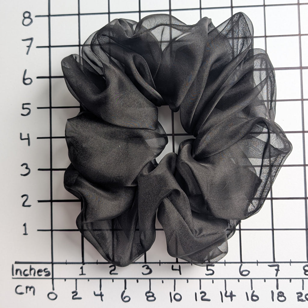 A  pure silk jumbo oversized black sheer organza hair scrunchie displayed on a white background with a black grid ruler showing inch measurements.