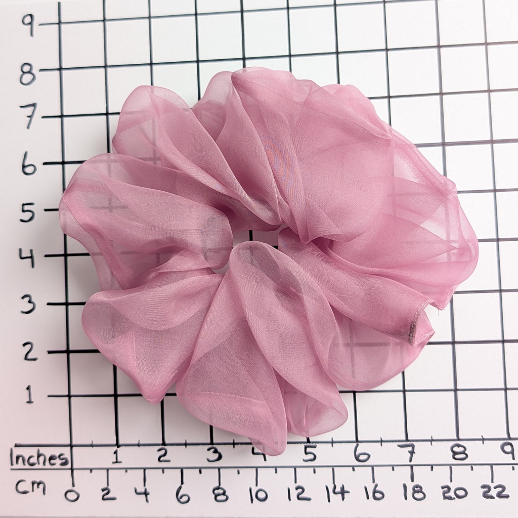 A dusty pink pure silk organza oversized jumbo sheer  scrunchie laid flat on a white background with a black grid ruler showing inch measurements.