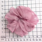 A dusty pink pure silk organza oversized jumbo sheer  scrunchie laid flat on a white background with a black grid ruler showing inch measurements.