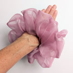 A dusty pink pure silk organza oversized jumbo  sheer  scrunchie worn on a person's wrist, 