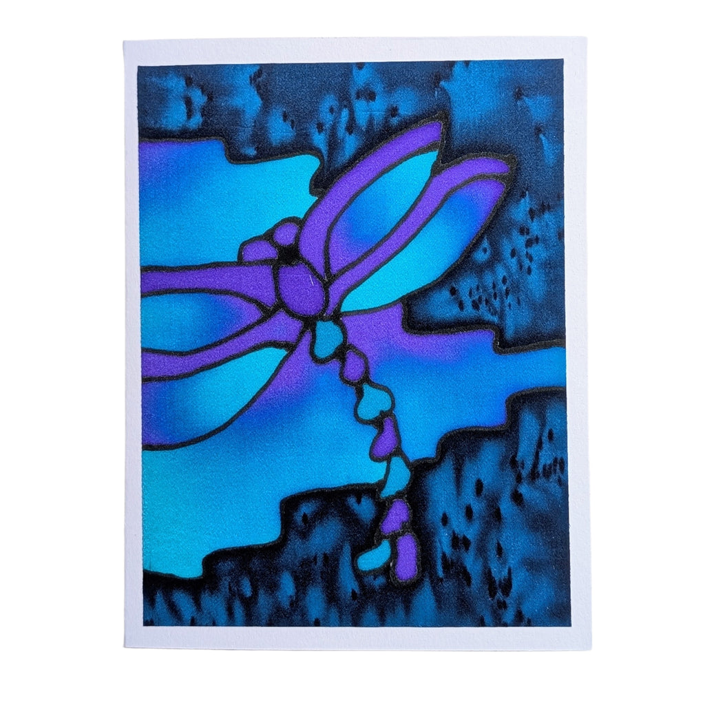 Hand painted pure silk original art greeting card featuring a stylized dragonfly in vibrant purple and light blue, set against a dark blue and black textured background, presented on a white paper sheet.