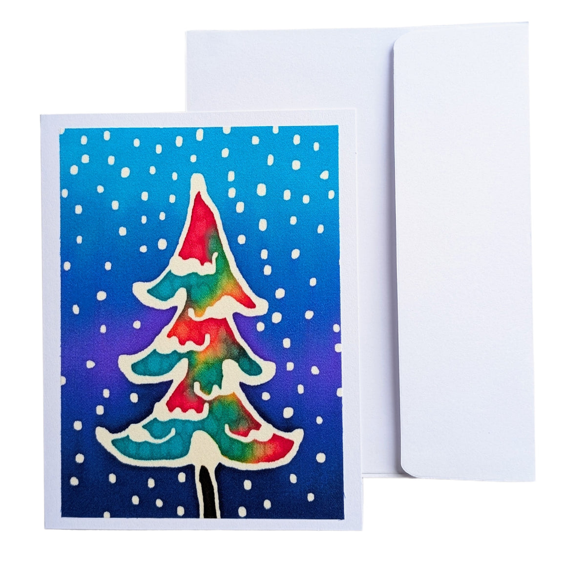 A Christmas greeting card featuring a colorful, hand painted pure silk original art Christmas tree on a blue and purple gradient background with white snowflakes, shown with a plain white envelope behind it.